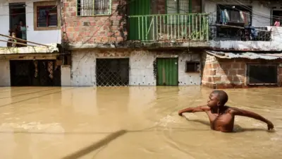 Un garçon patauge dans une rue inondée à Cali, en Colombie, le 11 novembre 2022.