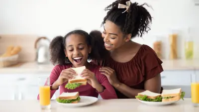 A child eating in front of her mother