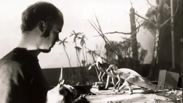 Black and white photo of a man working on dinosaur models