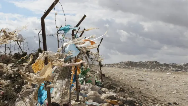 Пакеты с мусором развеваются как флаги на фоне пыльных мусорных холмов