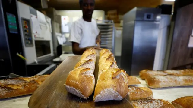 A baker in Nice shows off his baguettes