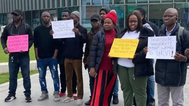 A group of Teesside University students hold placards