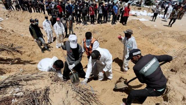 Trabalhadores palestinos exumando corpos no hospital Nasser com pás 