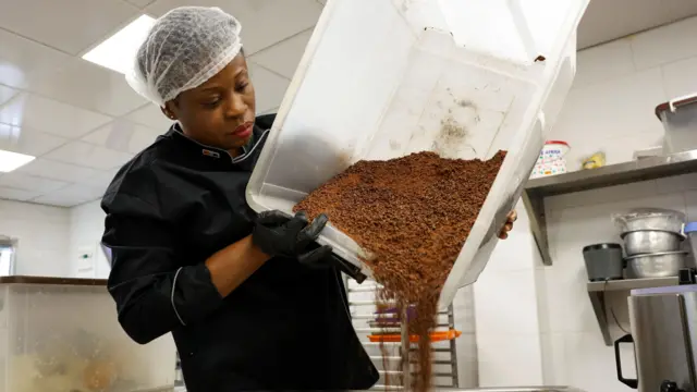 Chocolatier versant des fèves de cacao dans un mixeur 