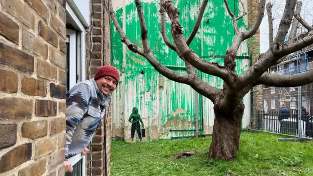 Carlos Serrano and the Bansky mural in Finsbury Park, London