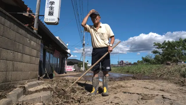 A man clears mud from his store following the passage of Typhoon Hagibis