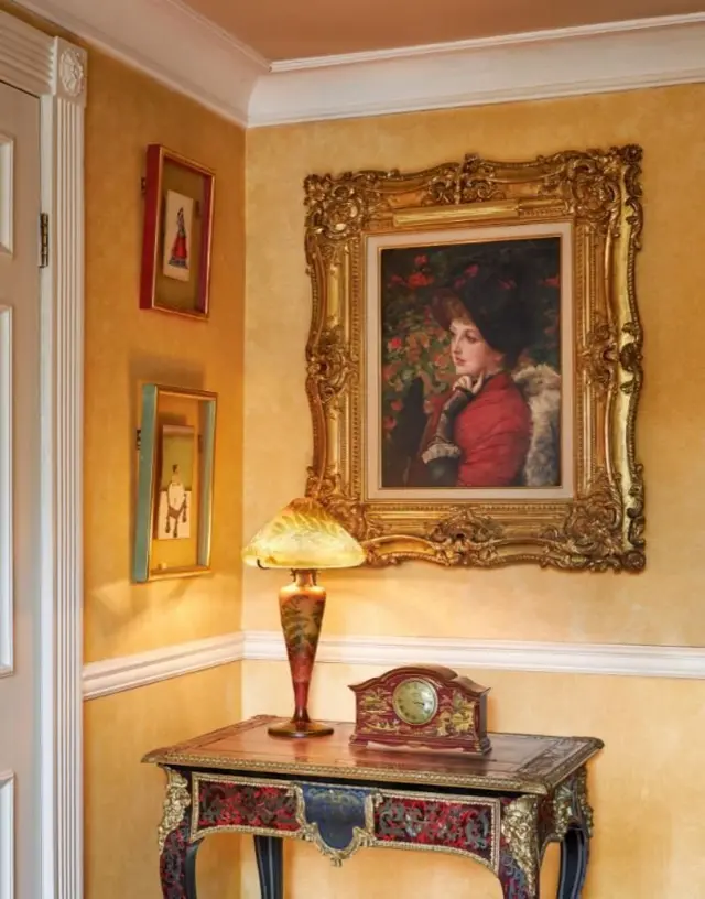 Портрет женщины на желтой стене над антикварным столиком
