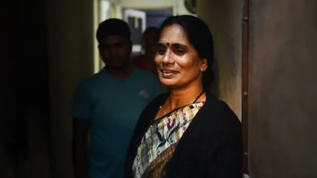 Женщина в индийском платье стоит в дверном проеме