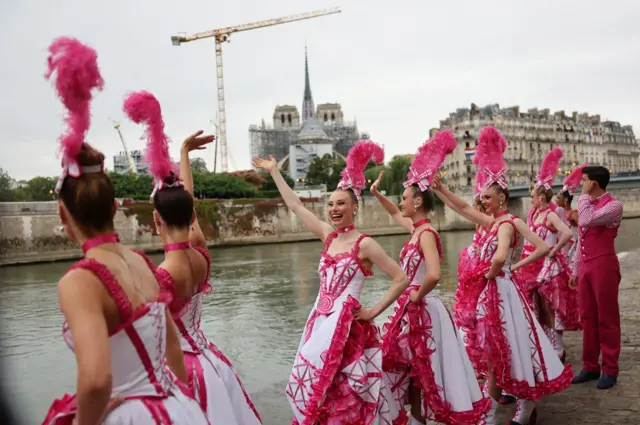 Dancers in pink and white dresses perform on the riverside during the opening ceremony of the 2024 Summer Olympics on July 26, 2024 in Paris, France.