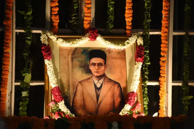 Portrait d'un Savarkar à lunettes, coiffé de son fameux chapeau rond et symétrique.