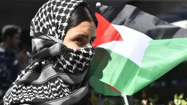 девушка в арафтке и с палестинским флагом