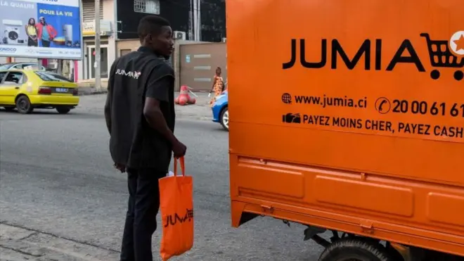 A delivery man stands next to a transporter with an advertisement for Nigeria's e-commerce site Jumia in Abidjan on June 13, 2019.