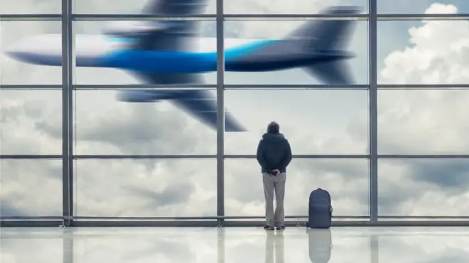 Человек в аэропорту наблюдает за взлетающим самолетом