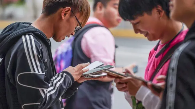 People on mobile phones outside a Nike store in Shanghai