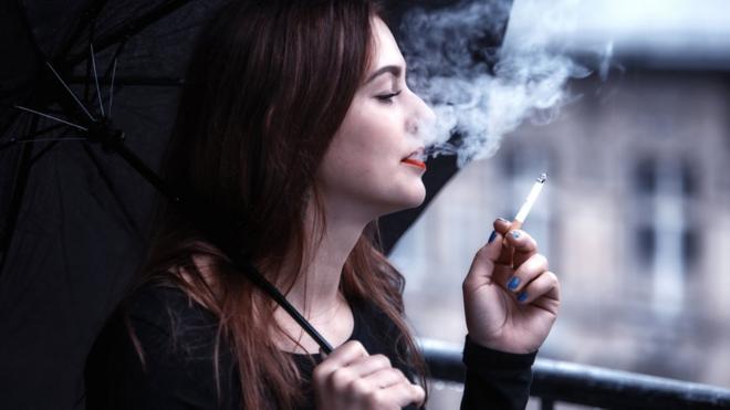 женщина курит на балконе