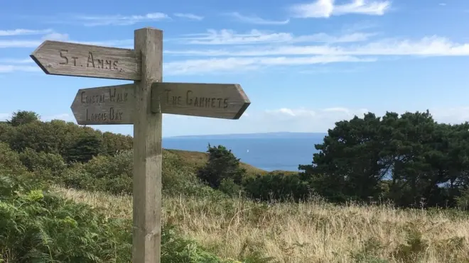 A coastal sign points tourists to Alderney's visitor attractions