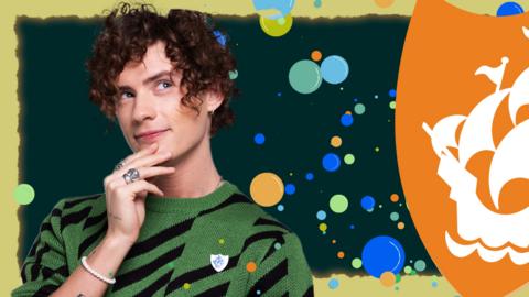 Joel holds a finger to his chin and puts on a puzzled face, there are colourful bubbles all around him and a large orange blue peter badge.