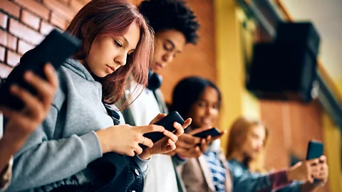 Teens looking down at their phones (Credit: Getty Images)