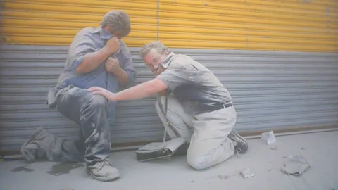 Two men take cover as dust from the collapse of the World Trade Center covers Manhattan (Credit: Getty Images)