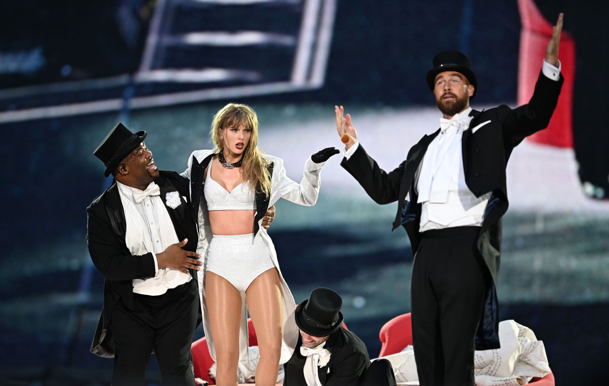 A dancer, Taylor Swift and Travis Kelce on stage. 