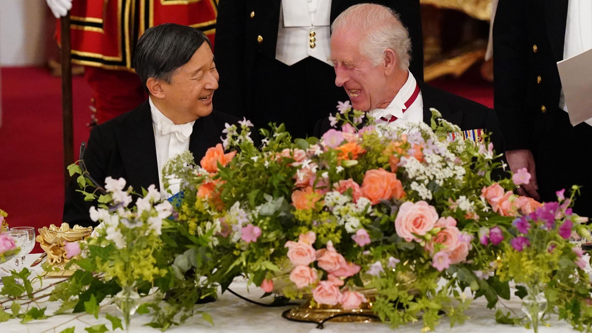 The Emperor and King laughing together, sat next to a large bouquet of flowers