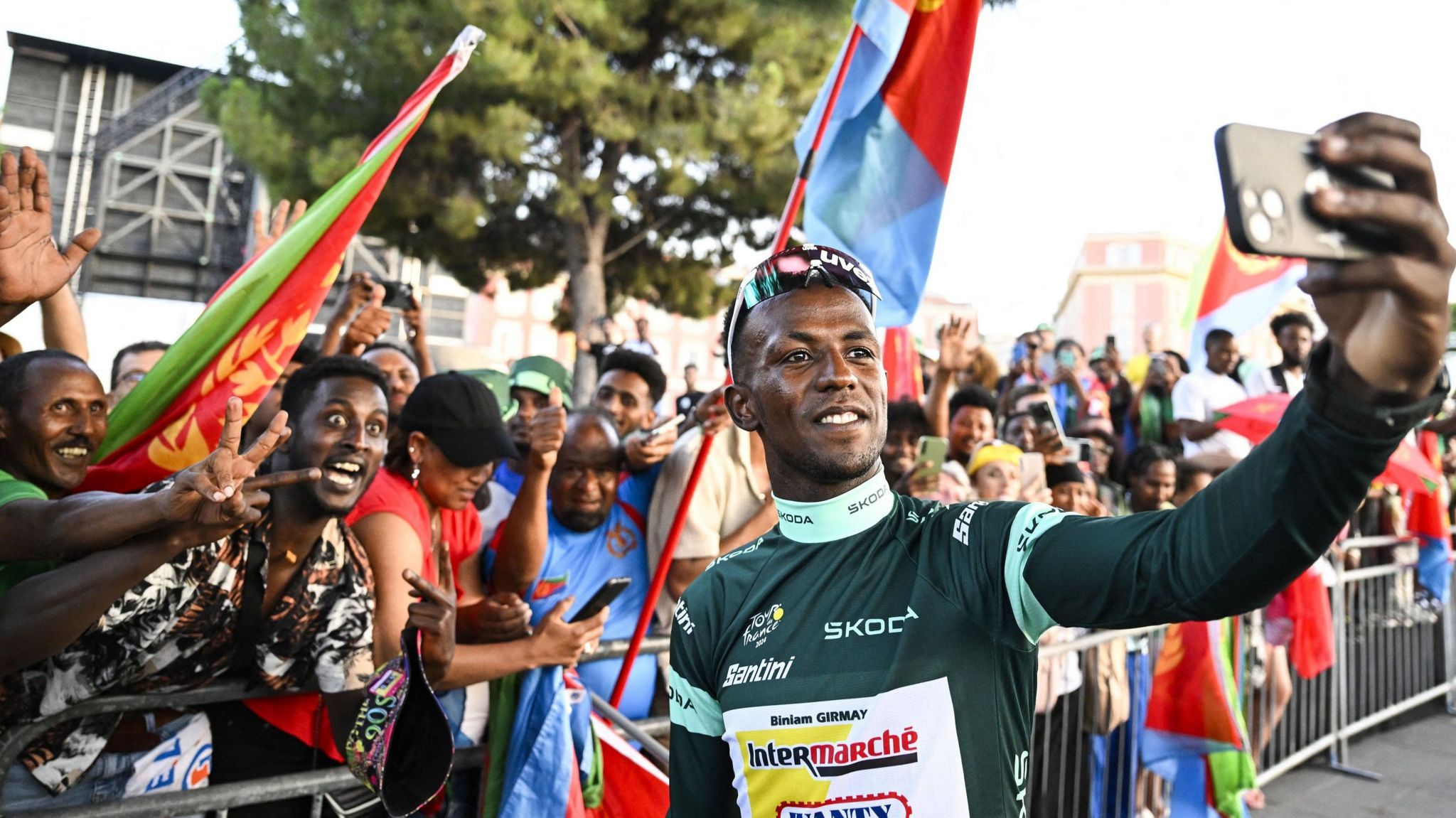 Biniam Girmay takes a selfie with fans from Eritrea who are holding flags