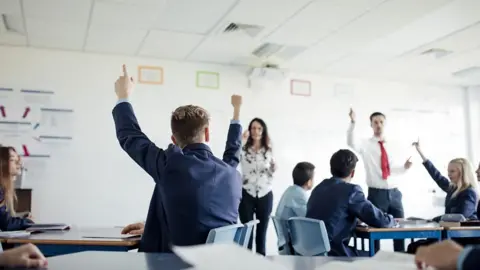 Children with hands up in a school classroom