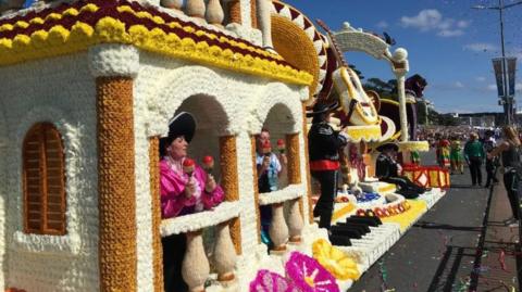People holding maracas on board a Mexican-themed floral float for Jersey's Battle of the Flowers parade