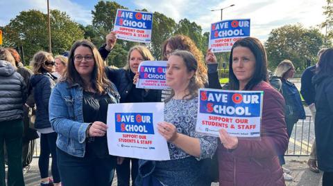Parents standing outside of the school in Durham holding placards that say 'save our school - support our students and staff'. Taken in September2023