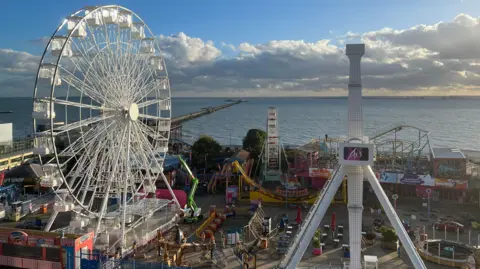 A view of Southend seafront with a white carousel and other amusement rides