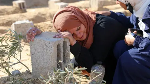 Reuters A Palestinian woman reacts at the grave of her son, who was killed in an Israeli strike, in Khan Younis, in the southern Gaza Strip (18 January 2024)