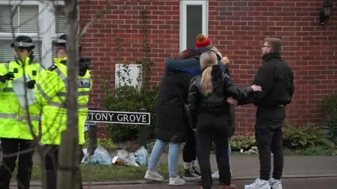 People lay floral tributes outside a house in Costessey, near Norwich