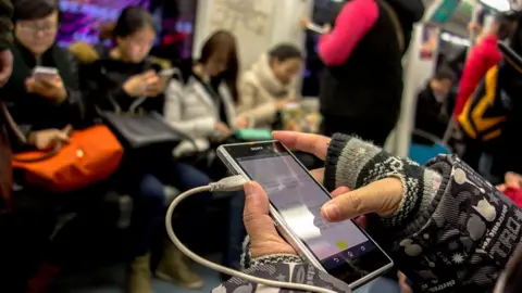 Getty Images Passenger holding mobile while on Beijing subway