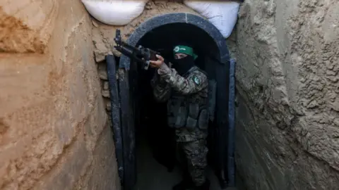 Getty Images Fighter belonging to Hamas’ military wing stands in front of tunnel in central Gaza strip on 19 July 2023