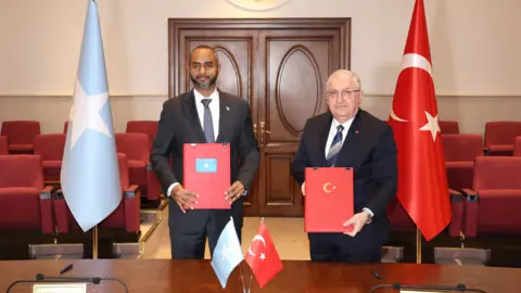 Somali and Turkish defence ministers pose in front of flags