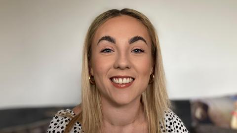 Gemma Cutler smiling at the camera in a black and white blouse