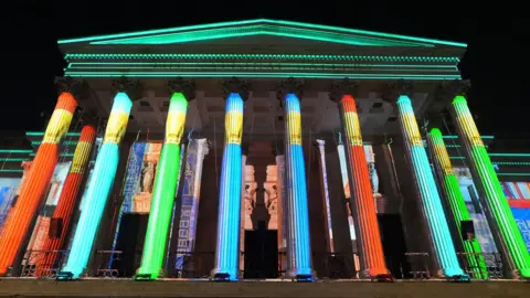 A light show is projected on to the side of the National Gallery