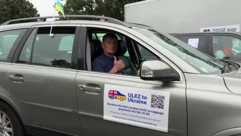 BBC Man sitting in a car with a Ukraine flag giving a thumbs up