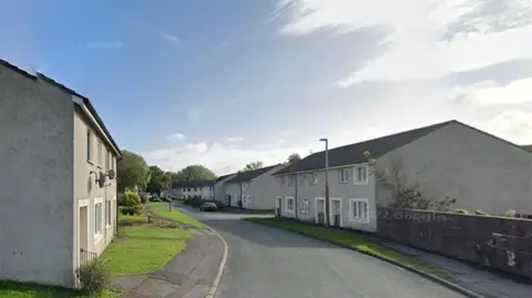 Pebbledash style houses on New Rough Hey in Preston line a street with gardens and lampposts