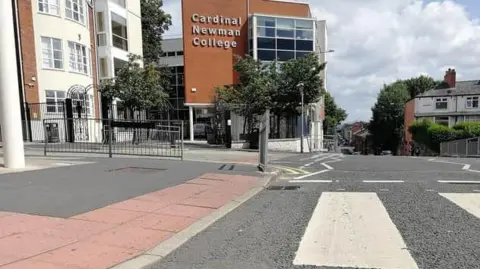A zebra crossing in front of the Cardinal Newman College building.