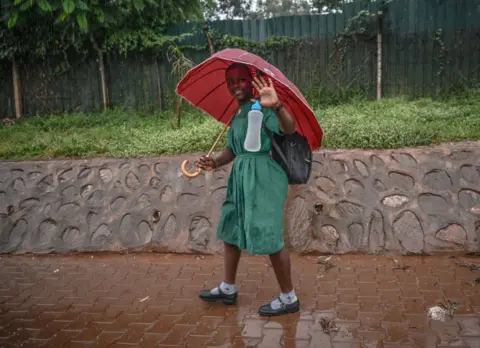 CEM GENCO/GETTY IMAGES A girl dressed in secondary school uniform walks in the rain in Kampala, Uganda, on Wednesday 24 July 2024