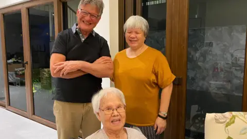 Professor David Britton (Left), Director of Creative Writing at Swansea University, in Singapore July 2022, with renowned writer and Swansea graduate Verena Tay (Right) and her mother, Mrs Tay (centre)