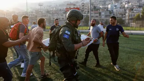 Israeli security forces and medics transport casualties from a site where a reported strike from Lebanon fell in Majdal Shams village in the Israeli-annexed Golan area on July 27, 2024