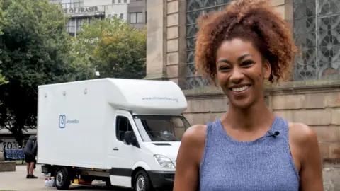 Woman next to white van which offers showers