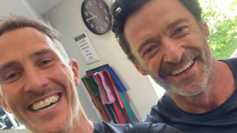 A selfie taken by Jules Greenway, who is on the left, with Hugh Jackman on the right. Both are smiling.