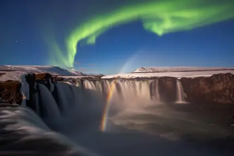 Mauro Tronto / Nature TTL The Northen Lights and a lunar rainbow seen above the Godafoss waterfall in Iceland.