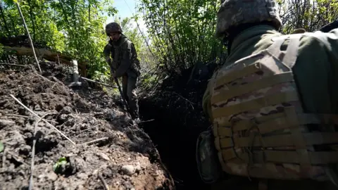 BBC/Lee Durant Ukrainian troops seek cover in trenches and behind the foliage of bushes on the outskirts of the city of Bakhmut