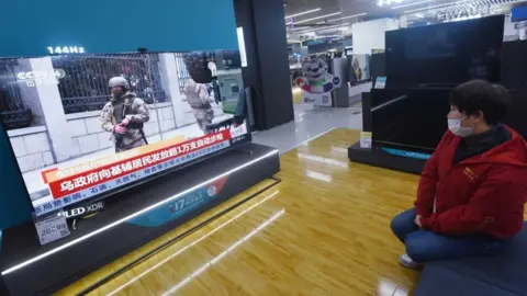 Getty Images Chinese women watching tv reporting on Ukraine