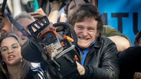 Getty Images Presidential candidate Javier Milei lifts a chainsaw during a rally on 25 September 2023 in San Martin, Buenos Aires, Argentina