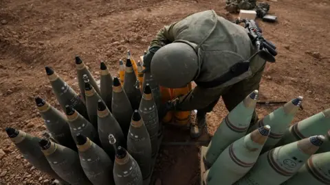 EPA An Israeli soldier checks artillery shells at an area along the border with Gaza, in southern Israel (9 October 2023)